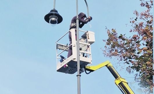 Człowiek na wysięgniku wymienia lampę w oświetleniu miejskim